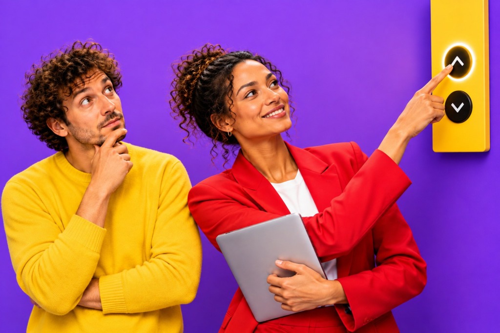 Twee collega's bij een lift, één denkt na terwijl de ander vol overtuiging op de knop drukt